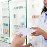 confident female pharmacist receiving medicine prescription from woman