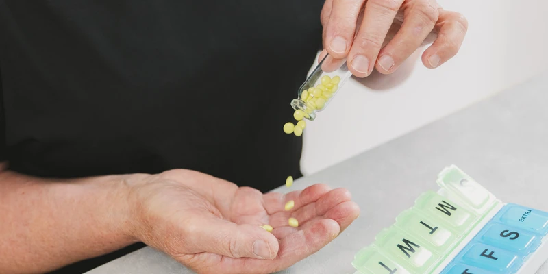 elderly woman pours yellow pills out bottle into