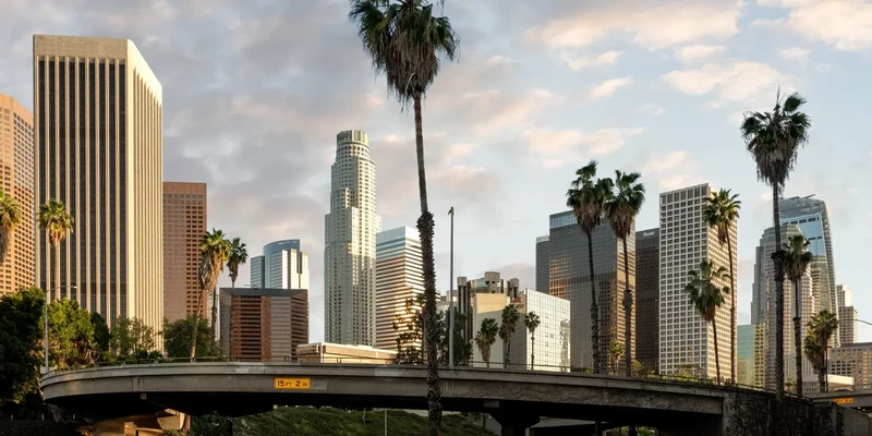 road by modern buildings against sky city sunset